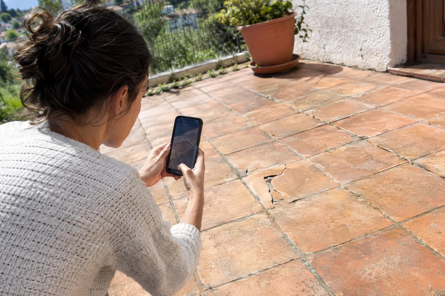 Une propriétaire photographie son ancien carrelage avec un téléphone pour demander un devis